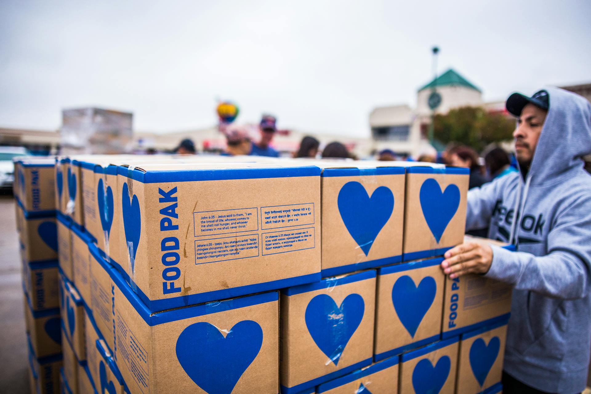 Volunteer organizing food donation boxes outdoors in an urban setting with a community focus.