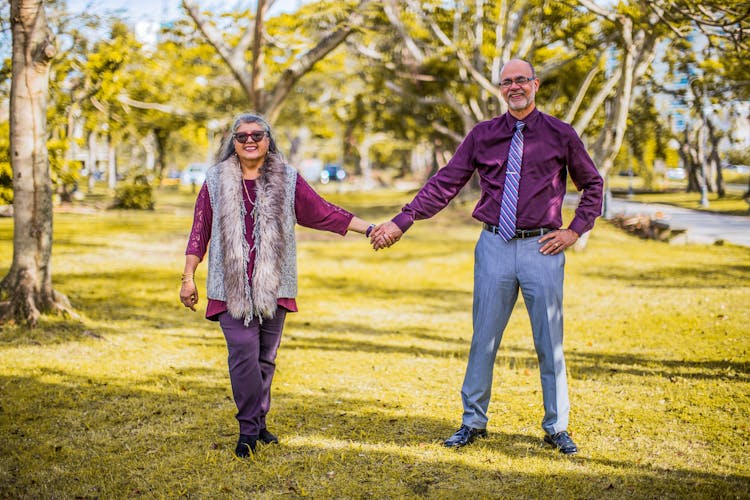 Cheerful Mature Couple Standing And Holding Hands In Park