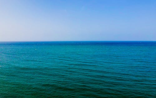 Picturesque turquoise sea with small waves under cloudless blue sky in sunny day