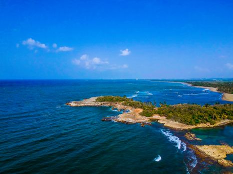 Stunning aerial shot of a lush, tropical coastline with vibrant blue waters and clear skies.