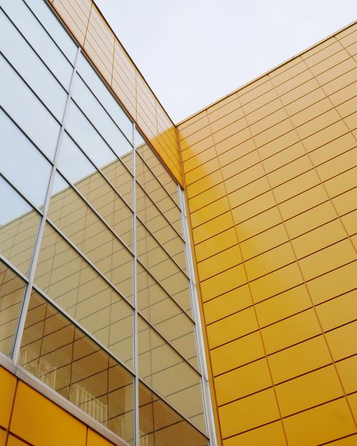 Free Contemporary architecture featuring a yellow facade and reflective glass elements. Stock Photo