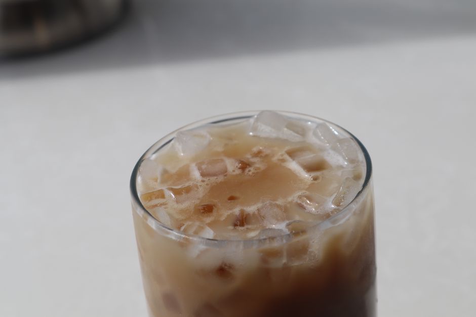 From above glass of refreshing iced coffee with milk served on white table in daylight
