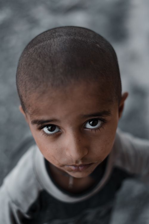 Free Heartfelt portrait of a young boy with a contemplative expression looking up. Soft lighting accentuates his soulful eyes. Stock Photo