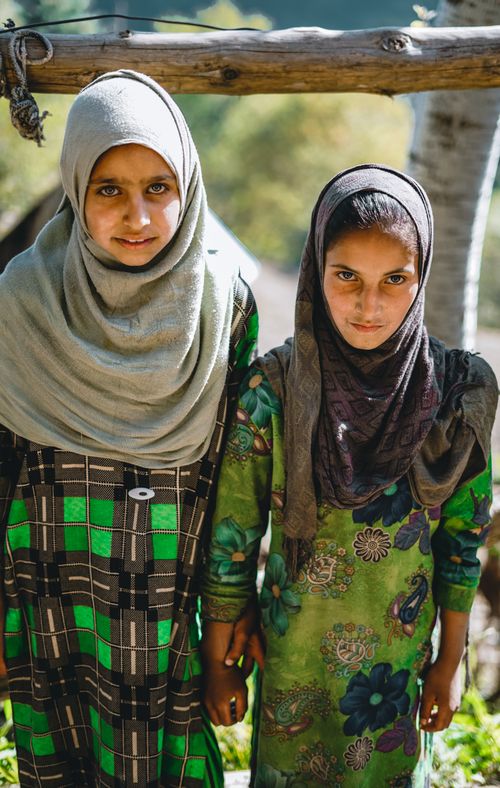 Free Portrait of two young girls wearing hijabs and green dresses, holding hands. Stock Photo