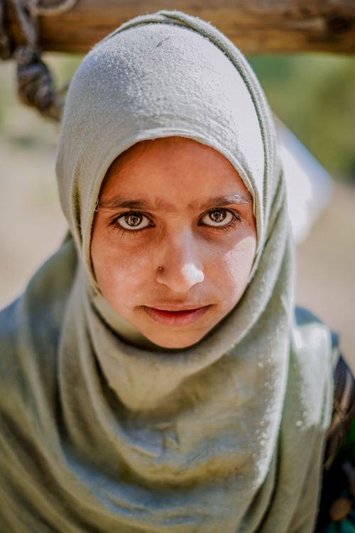 Free A close-up portrait of a young girl in a light green hijab. Natural light and serene expression outdoors. Stock Photo