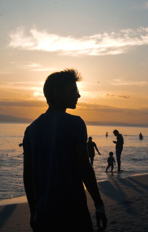 Free Silhouetted figures enjoy a scenic sunset on a serene Indian beach, capturing a tranquil seaside moment. Stock Photo