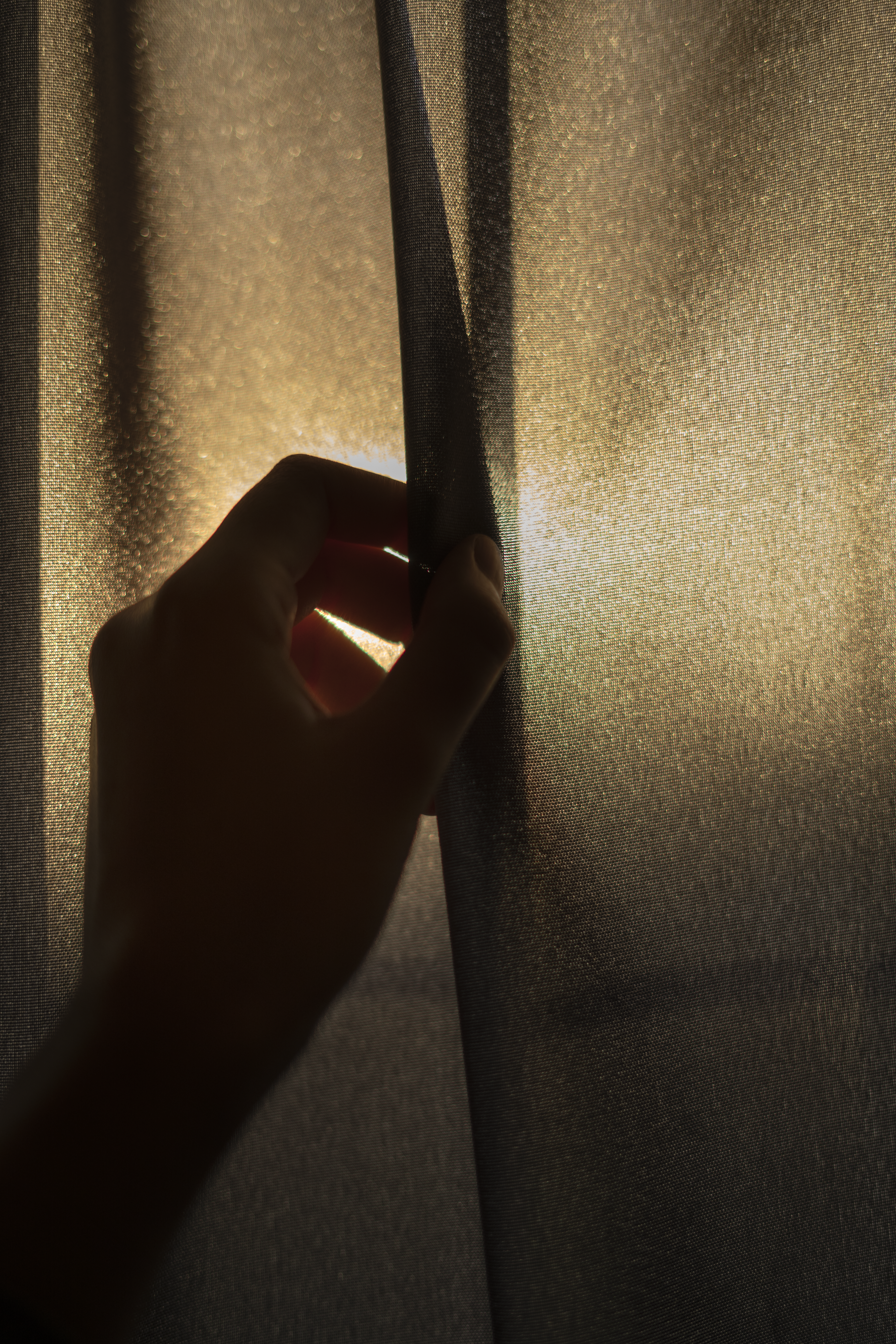 Hand on a curtain evoking shutter curtains and light control during leak checks.