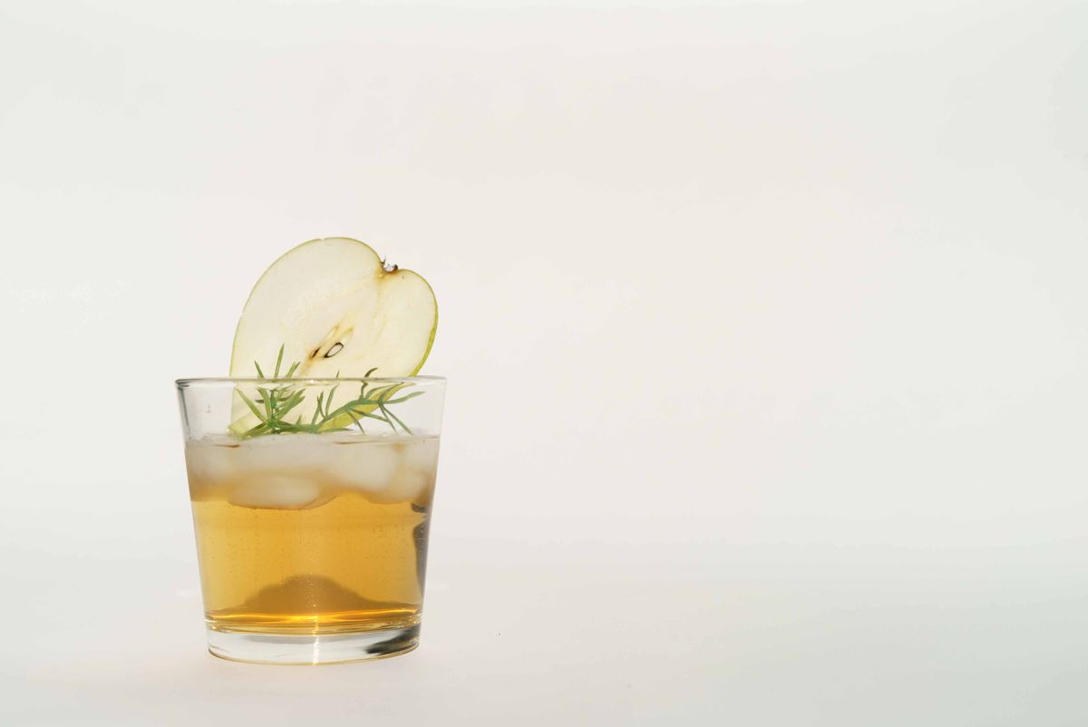 A clear cocktail with apple and herbs