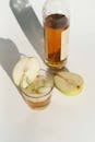 From above of crystal glass of pear brandy served with ice cubes and rosemary twig near bottle