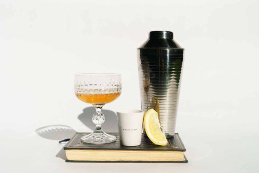 Glass of cognac with coffee and shaker on book