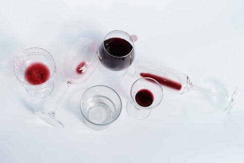 Top view of various crystal wineglasses with red wine placed on white background