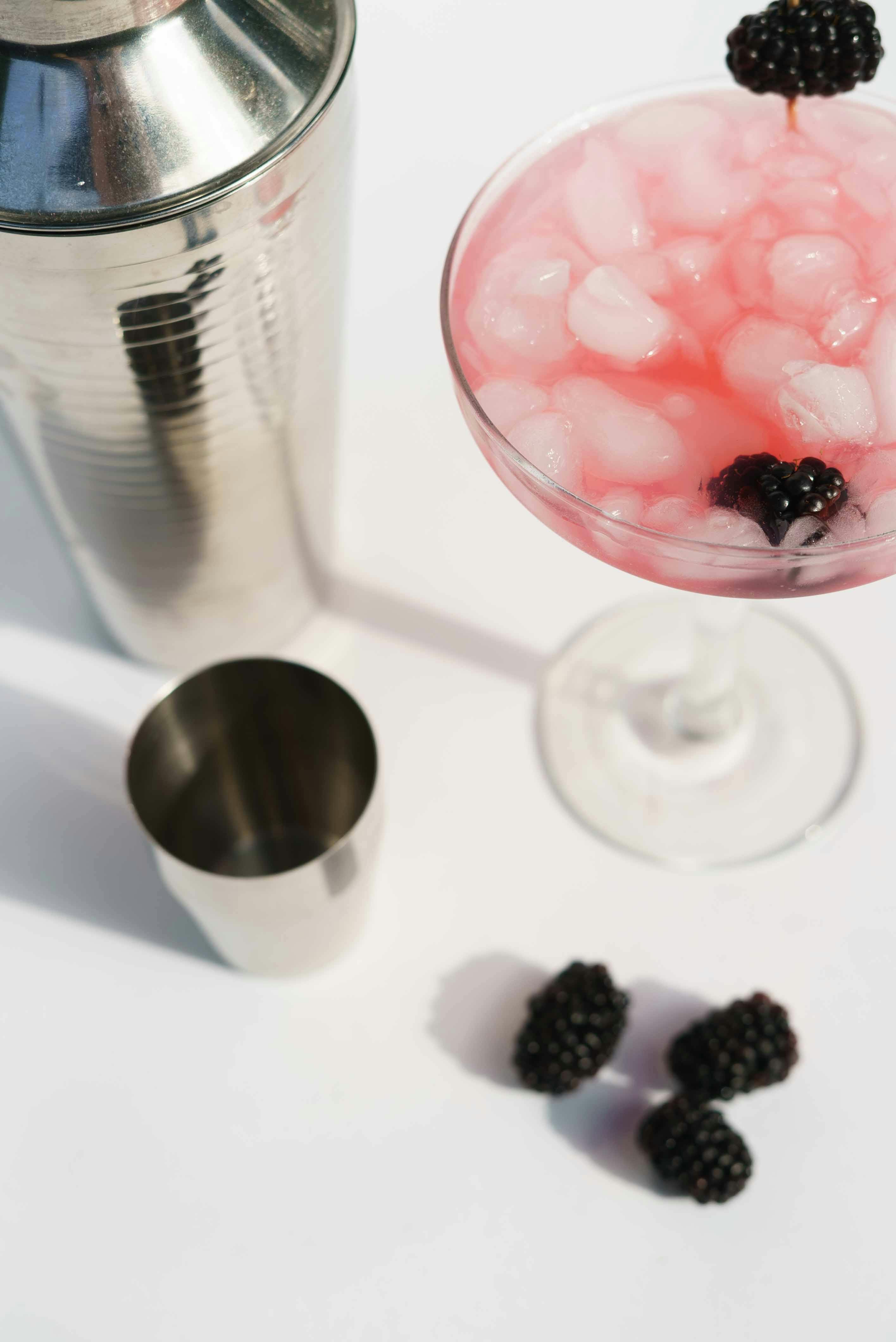 shaker and glass of margarita cocktail with blueberries