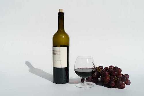 Free Red Wine Bottle beside a Wine Glass Stock Photo