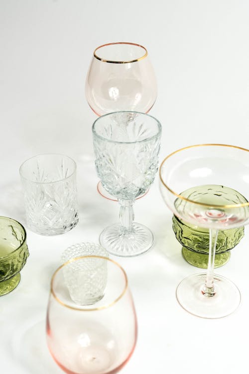 Set of transparent empty glasses for different drinks with various shapes and color placed on white background in light studio