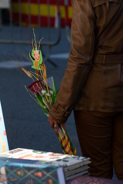 Person in Brown Jacket Holding a Red Rose