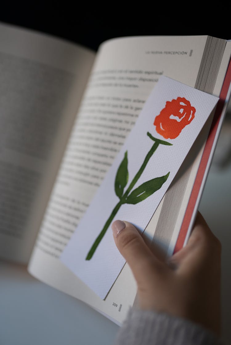 Person Holding A Rose Bookmark And A Book