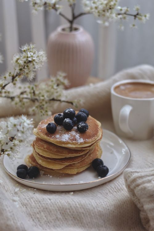 Free Delicious stack of blueberry pancakes in a cozy setting with flowers and coffee. Stock Photo