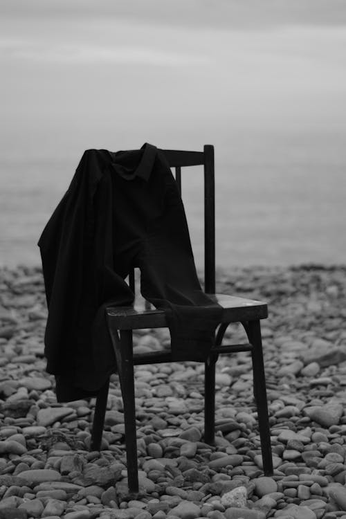 Grayscale Photo of Shirt Hanging on a Chair