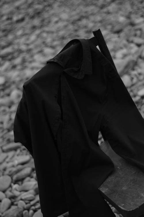 Grayscale Photo of Shirt Hanging on a Chair