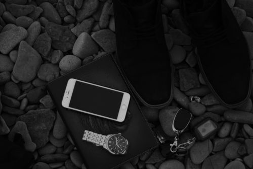 Free Black and white from above of crop unrecognizable person standing on pebbles with wristwatch and modern cellphone near car key Stock Photo