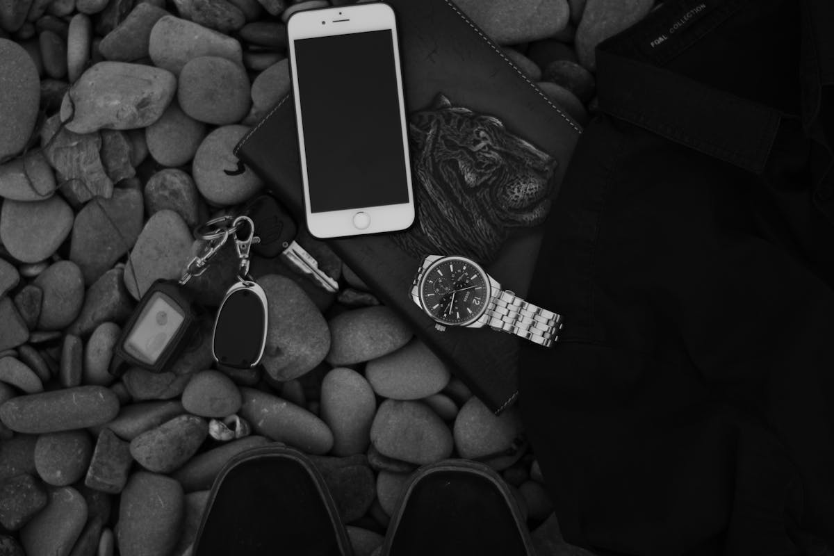 Faceless person and smartphone with wristwatch on pebbles