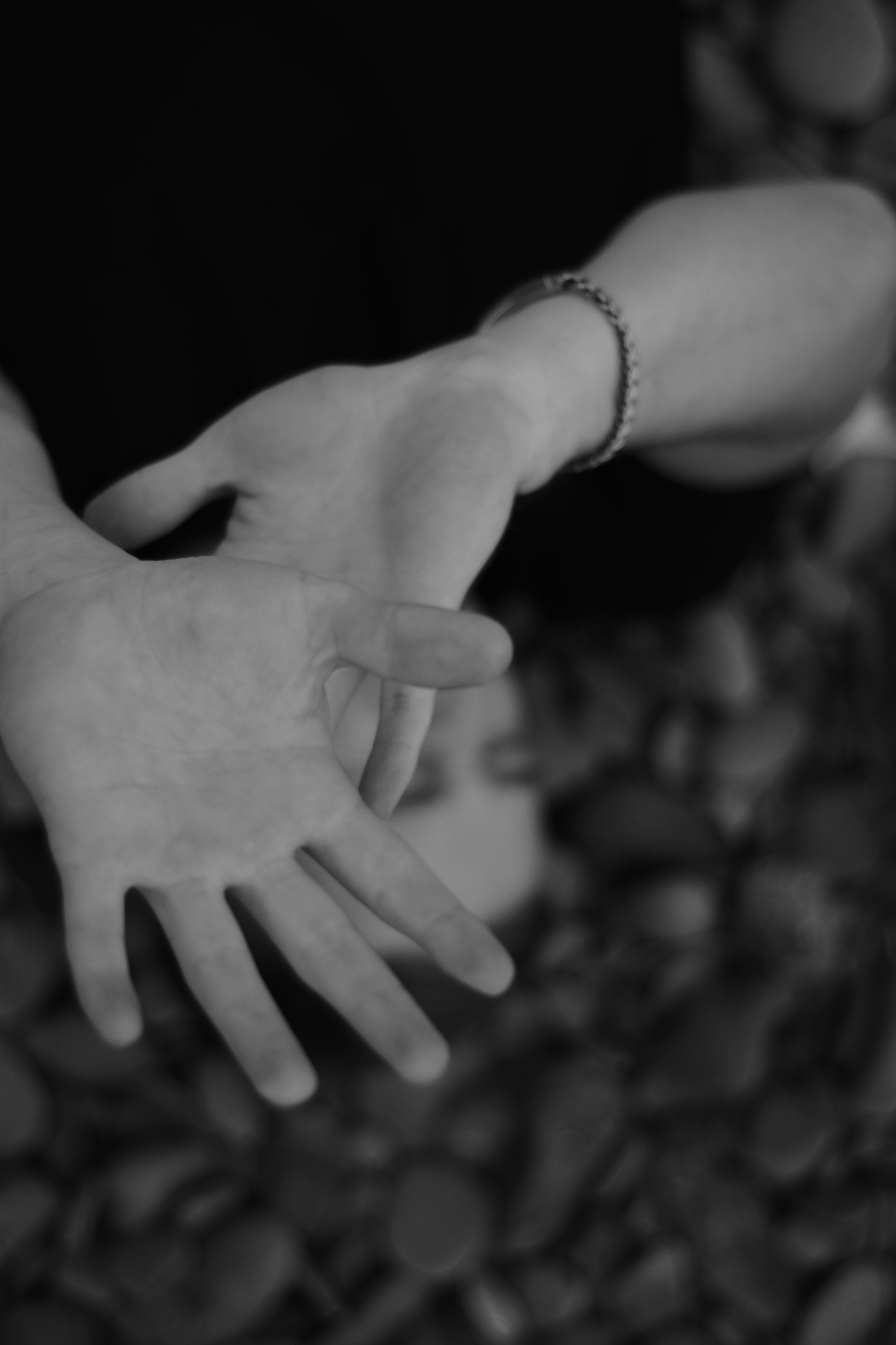 Fotomural Primer plano en blanco y negro de manos expresivas mostrando emociones sobre un fondo de roca desenfocado.