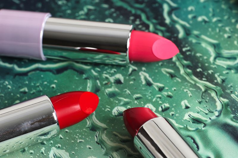 Pink and red lipsticks on a green surface