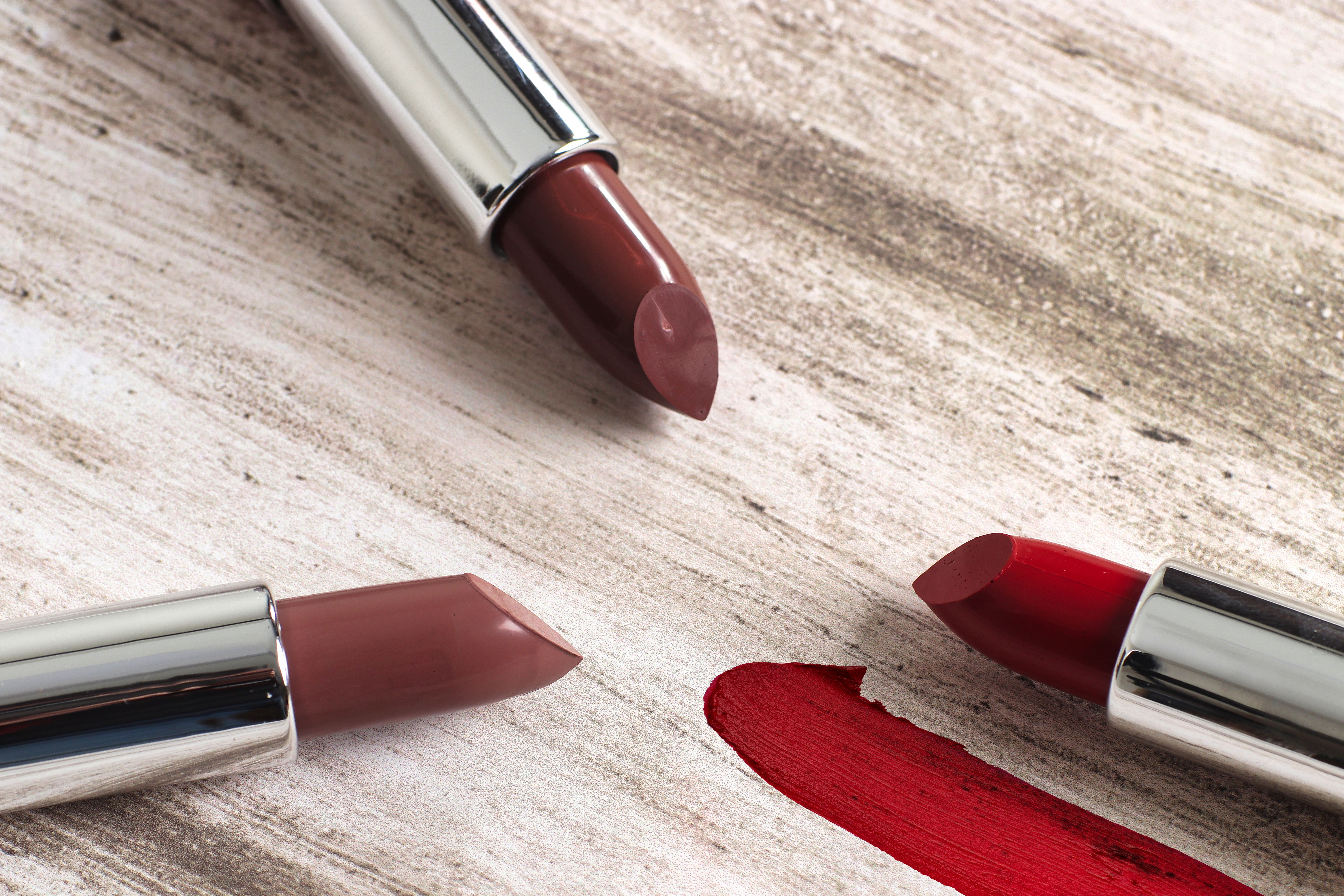 Various shades of lipsticks arranged on a rustic surface. Ideal for beauty and cosmetic content.