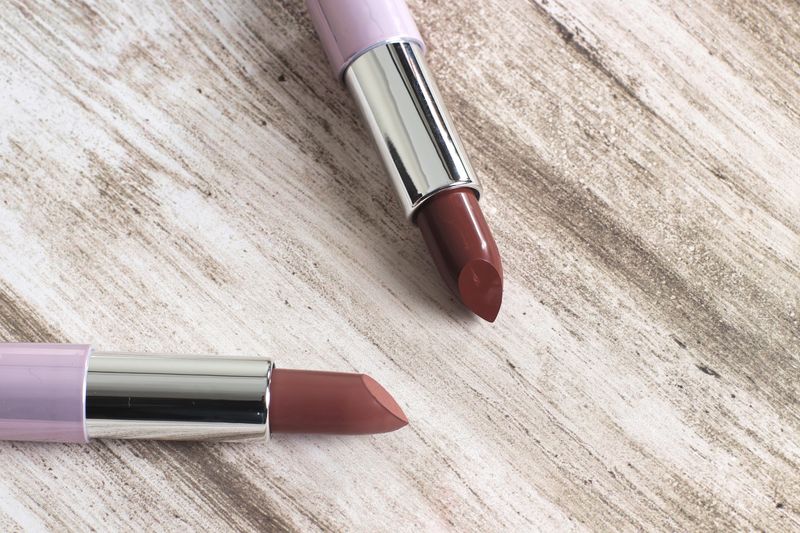 Close-up of two elegant lipsticks on a rustic wooden surface, showcasing beauty and style.