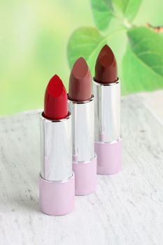 Close-up of three lipsticks with vivid colors on a marble surface, perfect for beauty and cosmetics themes.