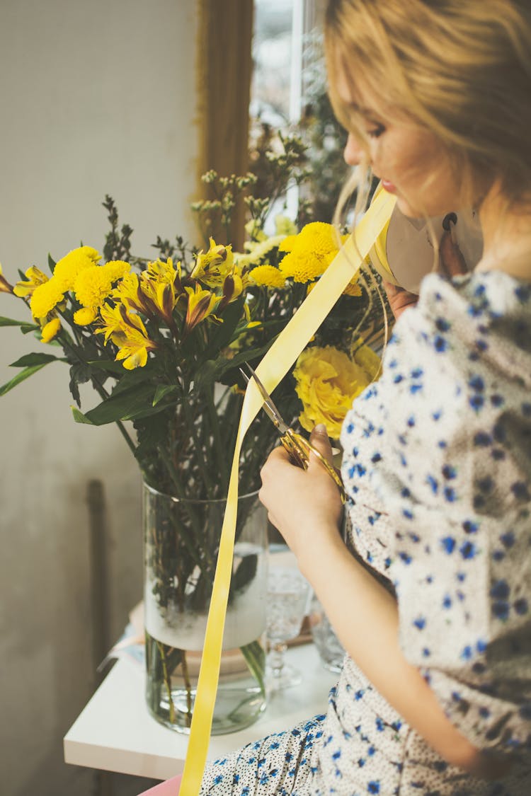 Woman Cutting Ribbon For Bouquet In Vase