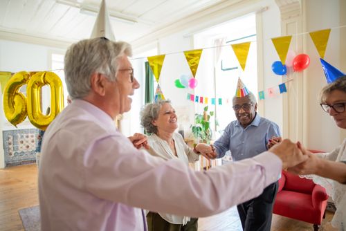 Free Group of seniors celebrating a birthday indoors with party hats and decorations. Stock Photo