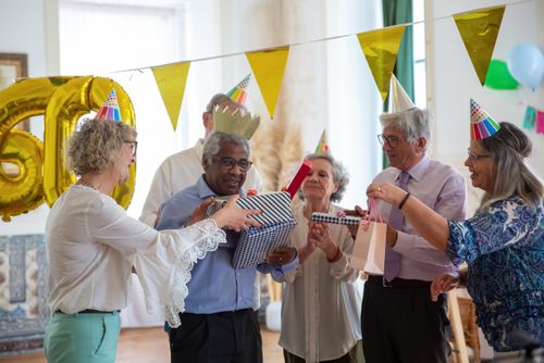Free Group of senior adults celebrating a birthday with gifts and decorations indoors. Stock Photo