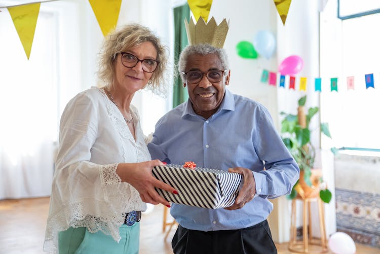 An Elderly Woman Handing A Gift To An Elderly Man