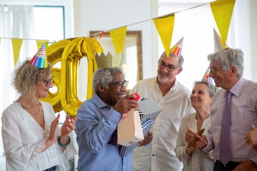 Free Seniors celebrate a birthday party indoors with gifts and laughter, a moment of joy and togetherness. Stock Photo