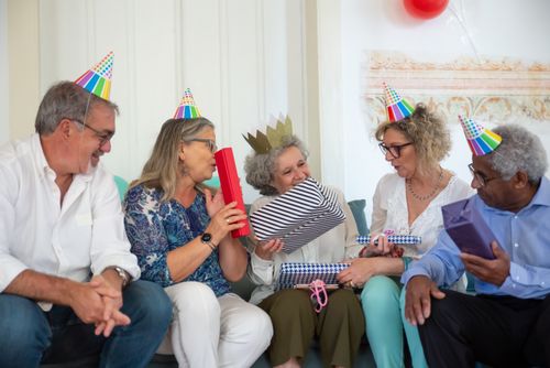 Free A group of smiling senior adults celebrating a birthday, exchanging gifts indoors. Stock Photo