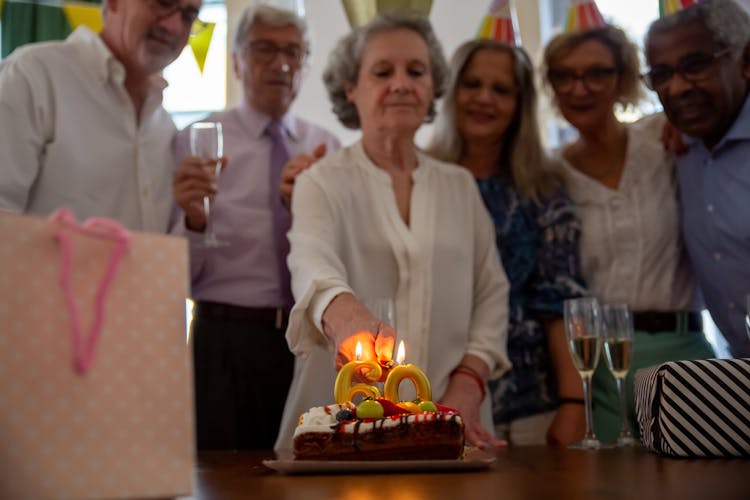 An Elderly Woman Lighting A Candle On A Birthday Cake