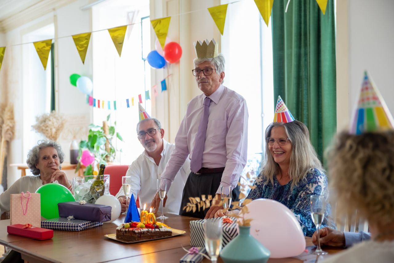 smiling seniors celebrating a birthday party indoors with decorations