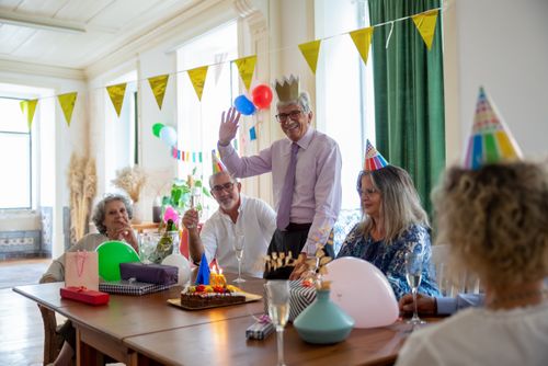 Free Joyful indoor birthday party for senior with friends celebrating with cake and decorations. Stock Photo