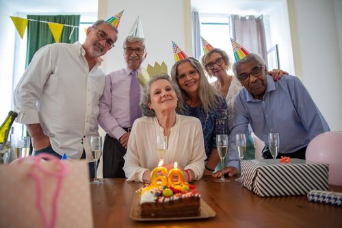 Free Group of senior adults celebrating a birthday with cake and gifts at an indoor party. Stock Photo