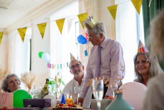 Seniors enjoying a cheerful birthday party indoors with cake and decorations in Portugal.