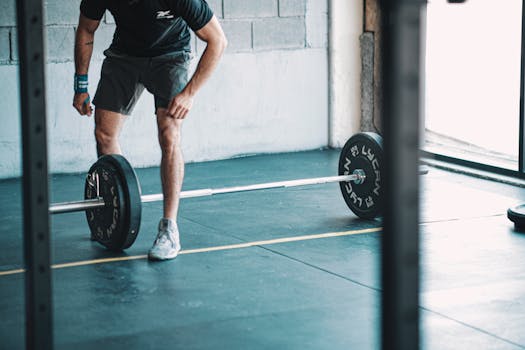 A man getting ready to lift a barbell in an indoor gym setting.