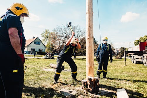 Free Man in Uniform Hammering the Wood Log of a Pole Stock Photo