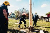 Man in Uniform Hammering the Wood Log of a Pole