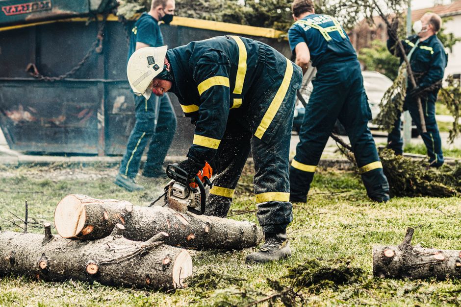 Crew in protective gear using chainsaws to clear fallen trees after a storm