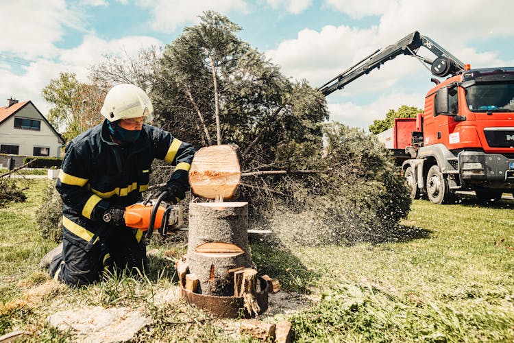 A Firefighter Cutting A Tree With A Chainsaw