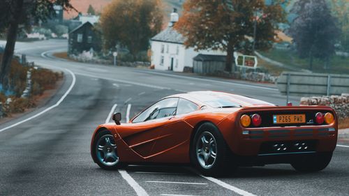 Free Luxurious sports car with sleek design on a curved road surrounded by trees. Stock Photo