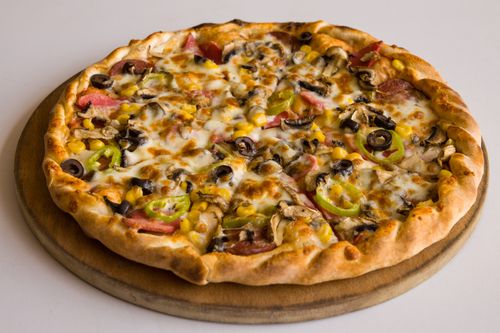 Free Appetizing pizza with olives, mushrooms, green peppers, and cheese on a wooden board. Stock Photo