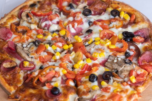 Mouthwatering close-up of an Italian pizza loaded with vibrant toppings like sausage, olives, and corn.