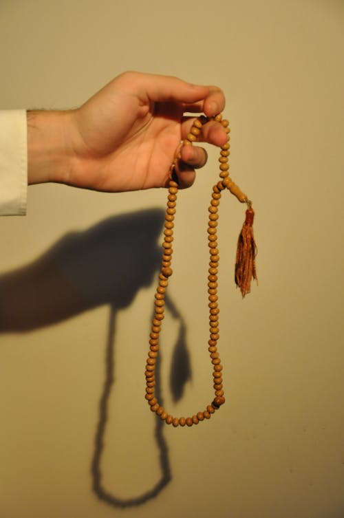 Hand of Person Holding a Wooden Beaded Necklace